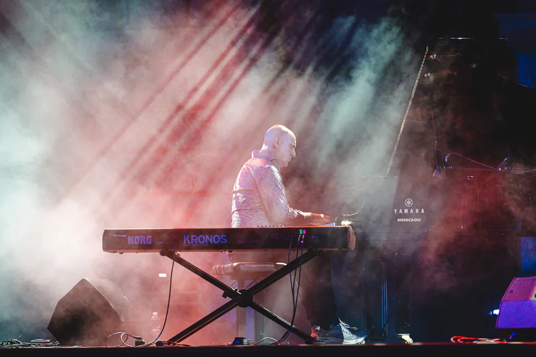 Un musicista alle tastiere fra le luci del concerto di Karima